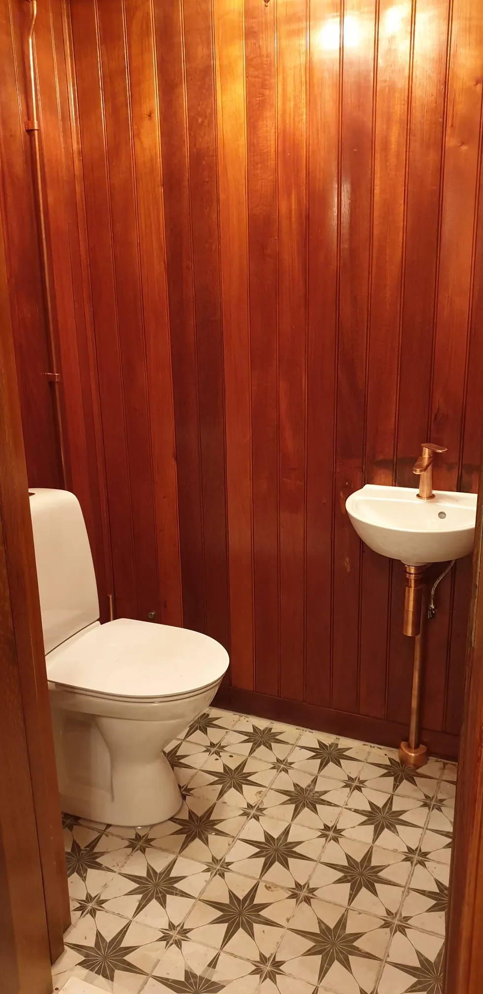 Gäst-WC med träpanel och stjärnkakel